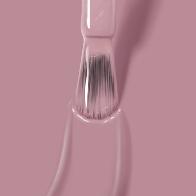 Close-up of a brush applying LONDONTOWN Plush (Professional) mauve crème shade nail polish on a surface, with visible bristles coated in the vegan, cruelty-free polish.