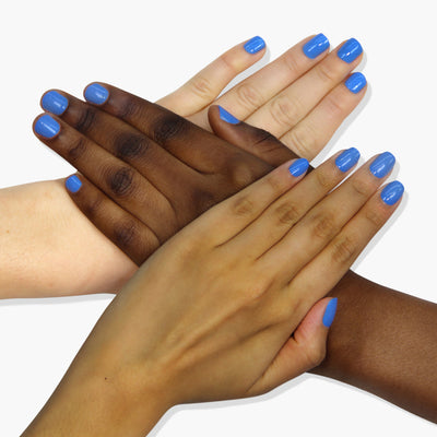 Four hands with different skin tones, all adorned with LONDONTOWN's Poolside Dreams blue vegan and cruelty-free nail polish, come together in an overlapping pattern against a white background.