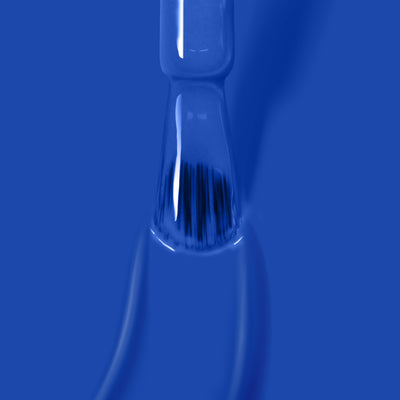Close-up of a LONDONTOWN Poolside Dreams gel color nail polish brush coated in blue against a matching blue background.