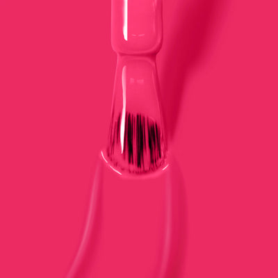 Close-up of a Queen of Hearts (Professional) nail polish brush from LONDONTOWN, showcasing bristles coated in the vibrant, cruelty-free deep fuchsia pink crème polish against a pink background—a perfect choice for your next party manicure.