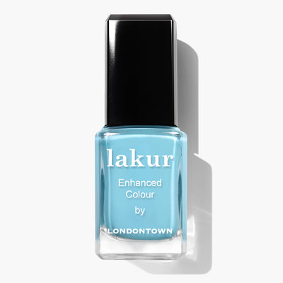A bottle of LONDONTOWN Reverse the Charges vegan nail polish with a blue shade and black cap. The label reads, "Lakur Enhanced Colour by LONDONTOWN." This cruelty-free nail polish offers vibrant color while being kind to animals.