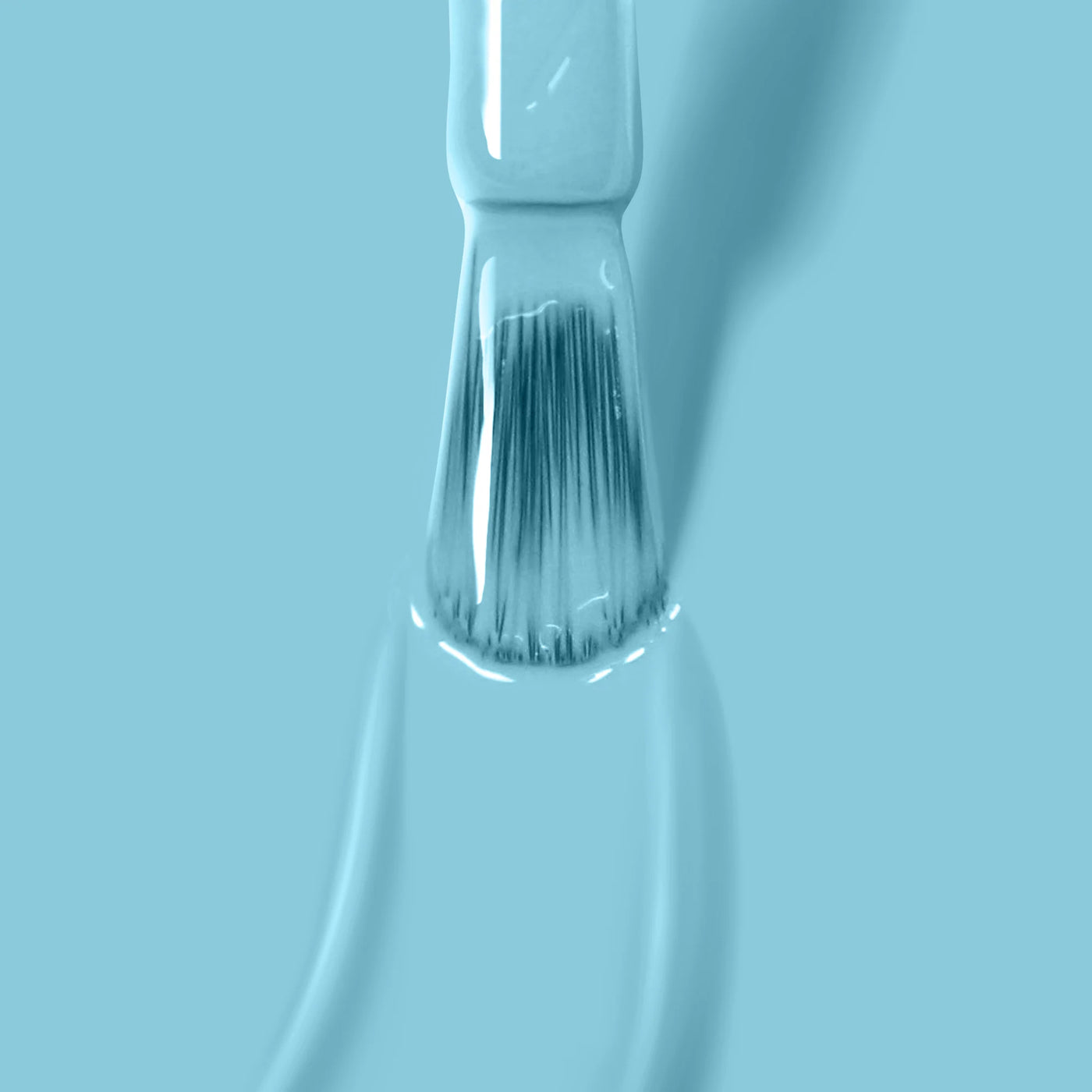 Close-up of a narrow paintbrush with light blue paint on its bristles against a matching blue background, reminiscent of LONDONTOWN's "Reverse the Charges (Professional)" serene aqua and turquoise nail polish collection.