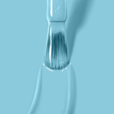 Close-up of a paintbrush with blue paint against a blue background, showcasing fine bristles and glossy wet paint that shimmers like the vibrant "Reverse the Charges" vegan nail polish by LONDONTOWN.