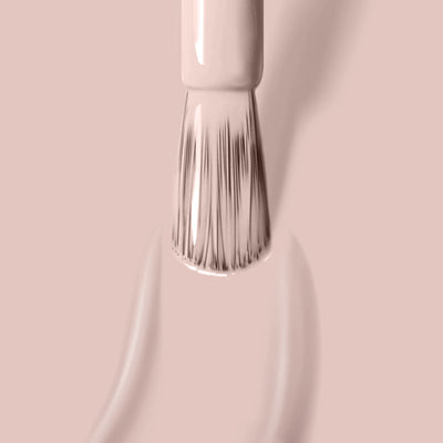 Close-up of a brush applying LONDONTOWN's Sandstone (Professional) polish, a light beige, antiqued white color, on a smooth surface, with brush bristles visible and two streaks of nourishing polish with Florium Complex being painted.