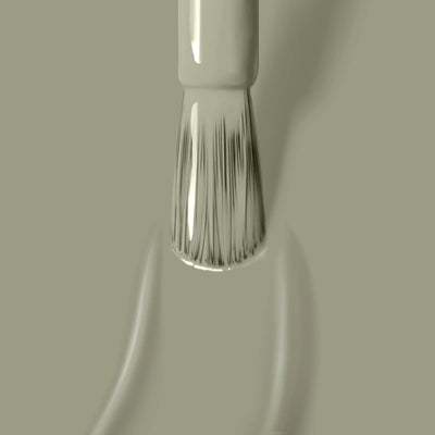 A close-up of a nail polish brush applying succulent Sedona jade green vegan cruelty-free nail polish from LONDONTOWN on a surface. The brush tips are slick with the glossy polish.