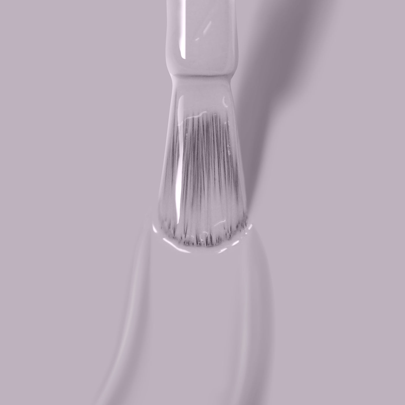 Close-up of a brush with Silver Birch vegan nail polish by LONDONTOWN on its bristles, against a light pink background.
