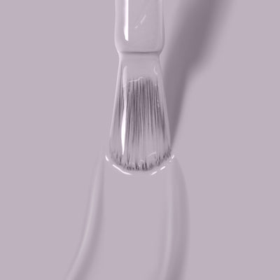 Close-up of a brush with Silver Birch vegan nail polish by LONDONTOWN on its bristles, against a light pink background.