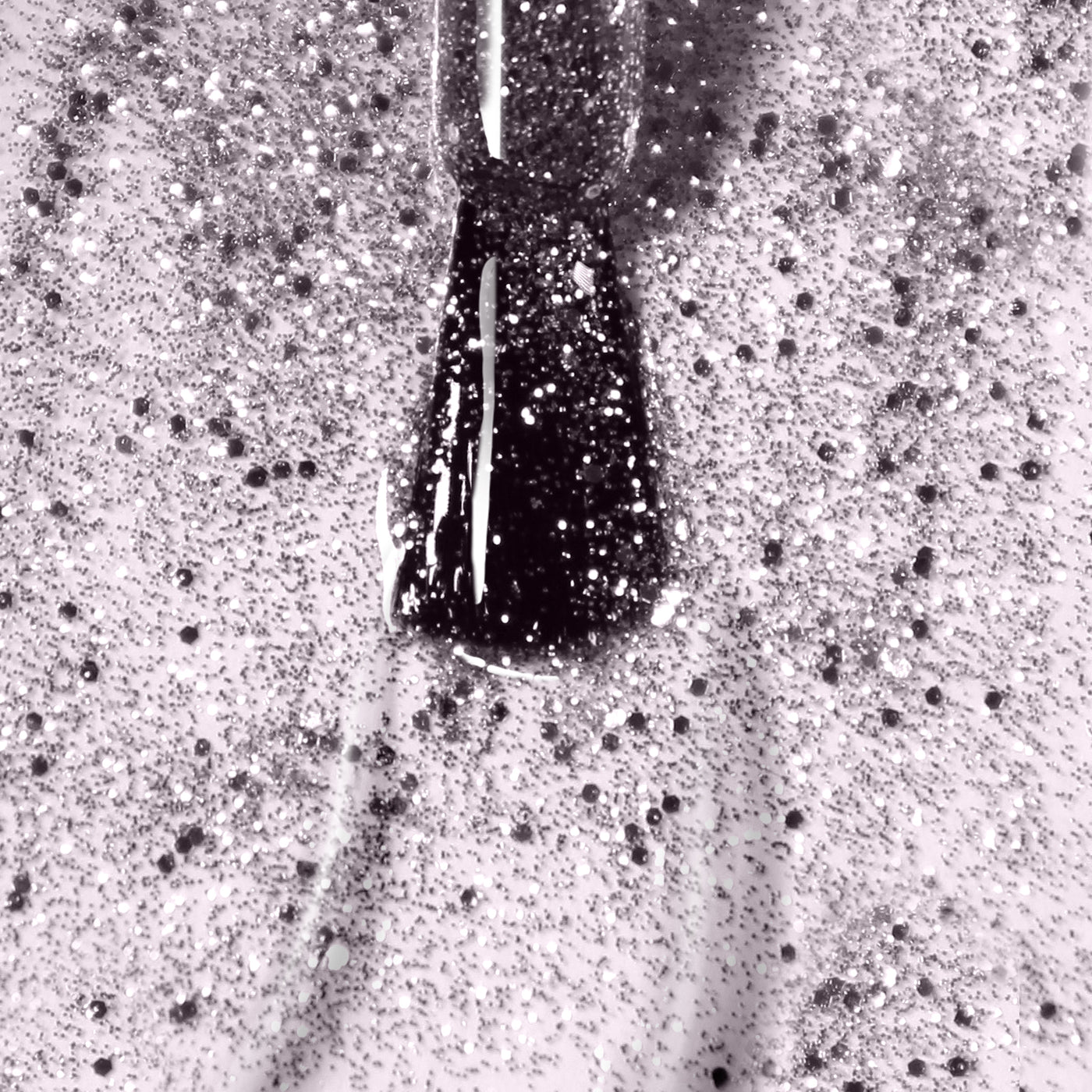 Close-up image of a nail polish brush applying a coat of LONDONTOWN's Starstruck, a vegan, glittery, speckled shimmer polish on a fingernail.