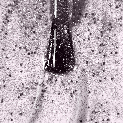 Close-up image of a nail polish brush applying a coat of LONDONTOWN's Starstruck, a vegan, glittery, speckled shimmer polish on a fingernail.