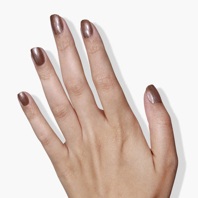 A hand with a shiny, metallic nude vegan nail polish from LONDONTOWN's Sugarcane collection.