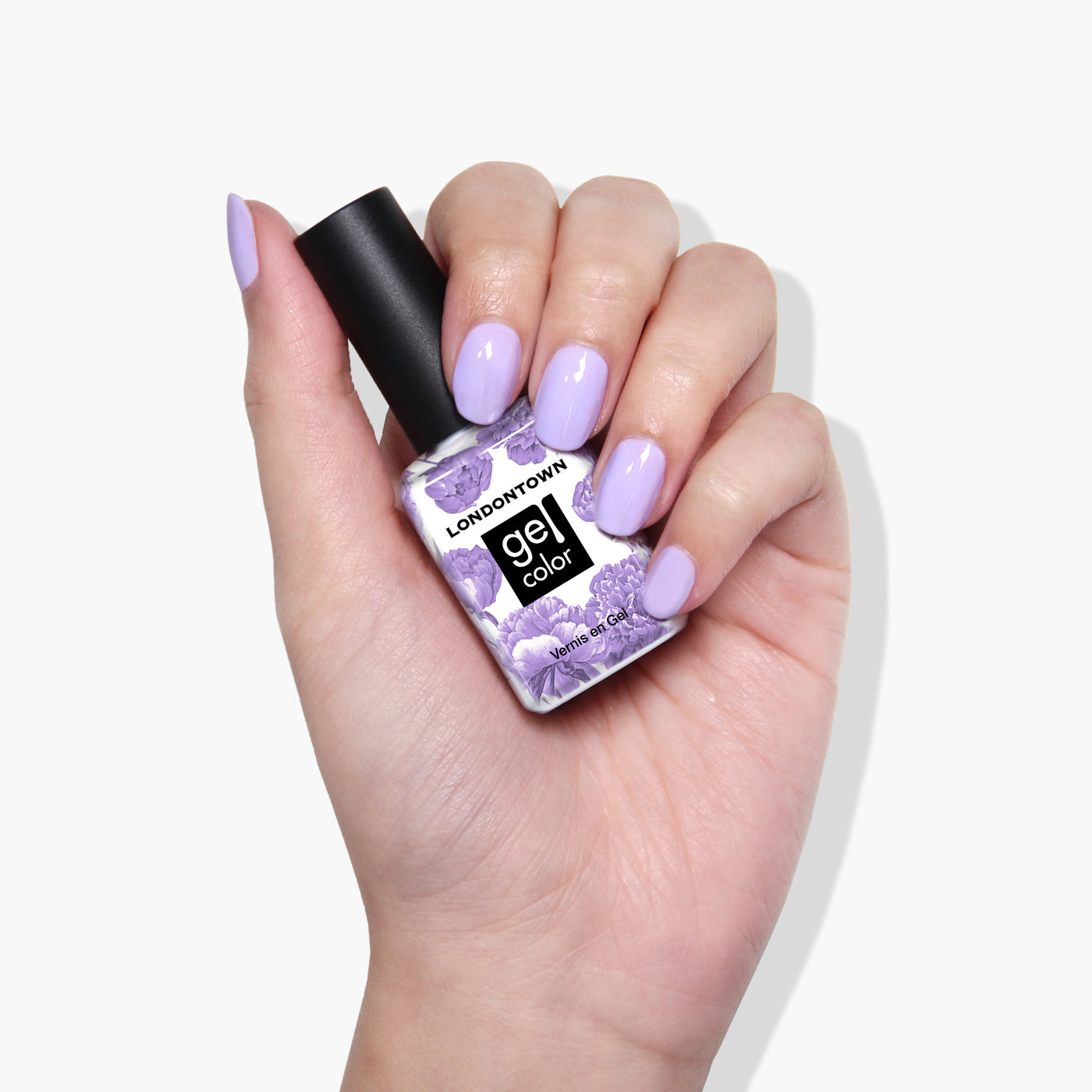 A hand with light purple painted nails holds a bottle of LONDONTOWN Trolley Away crème gel color nail polish.