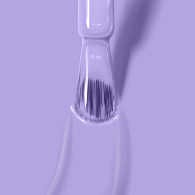 Close-up of a LONDONTOWN Trolley Away (Professional) nail polish brush applying lilac crème on a smooth surface, creating a glossy, even coat. The background is also light purple, providing a monochromatic aesthetic. This cruelty-free formula enhances beauty in an ethical way.