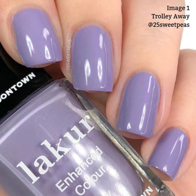 Up-close shot of a hand with nails painted in Trolley Away (Professional), a light lilac crème polish by LONDONTOWN. The bottle reads "lakur Enhanced Colour," though the shade name isn't completely visible. This vegan, cruelty-free formula provides your nails with a stunning, guilt-free appearance.