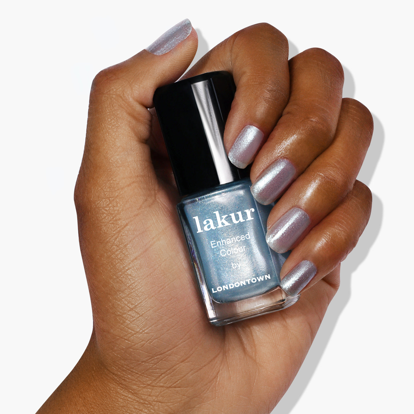 A hand with metallic silver nails holds a bottle of "Whipped Blueberry" nail polish by LONDONTOWN in a shimmery sky blue shade, featuring ultrafine glitter.