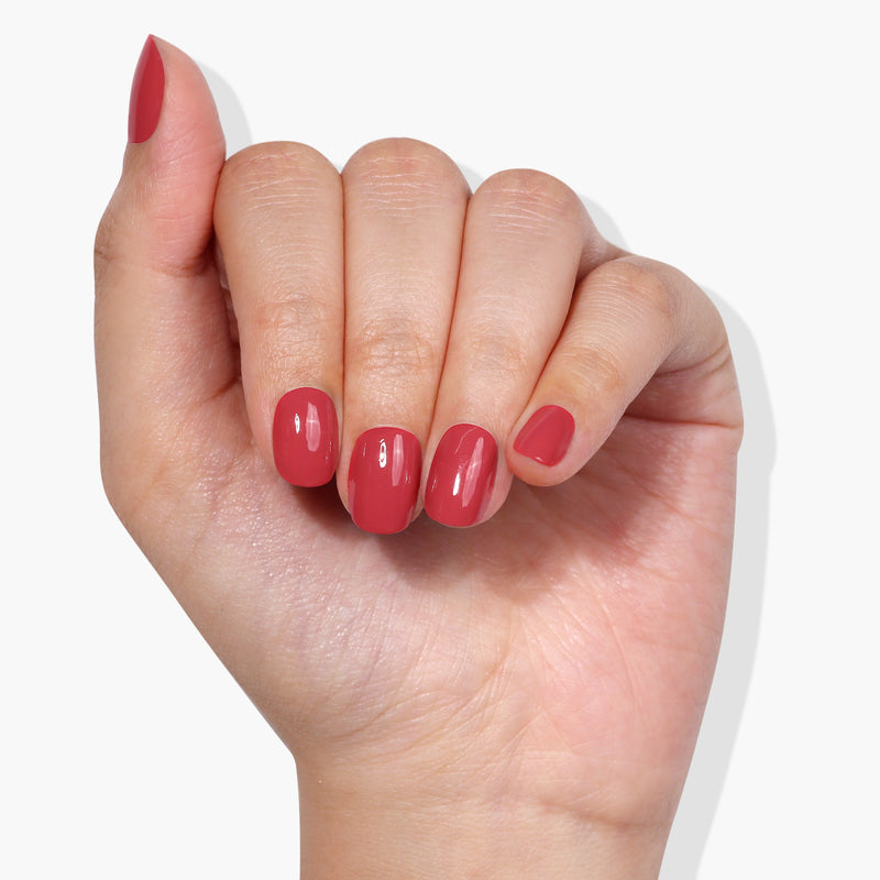 A hand showcases polished fingernails painted in a glossy, sun-kissed shade of LONDONTOWN's Flushed Cheeks against a white background.