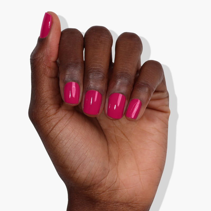 A hand with medium-dark skin tone displays five fingers with short, neatly manicured nails painted in a glossy, fruity pink polish from LONDONTOWN's Teeny 'Kini collection, against a white background.