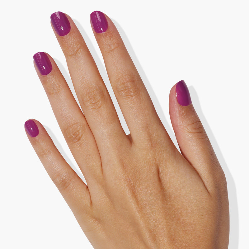 A hand with neatly trimmed nails painted in LONDONTOWN's Violet Hibiscus against a plain white background.
