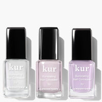 Three bottles from LONDONTOWN's Illuminating Nail Concealer Trio are arranged side by side in clear, light pink, and light purple shades.