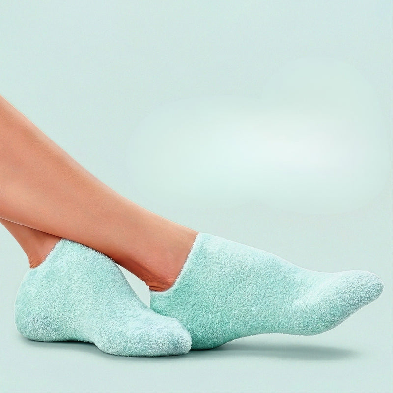 A pair of feet wearing Pedi Perfect Moisturizing Spa Socks by LONDONTOWN in light blue is displayed against a matching background; the description features only an image and color details, without specific product information.