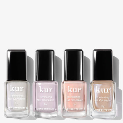 Four bottles of LONDONTOWN’s The Concealer Wardrobe are arranged in a row, each showcasing a different shade in clear glass bottles with sleek black caps for effortless nail perfection.