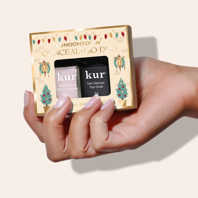 A hand holds the LONDONTOWN Conceal & Go - Pink: Holiday Edition, a festive nail polish set with Illuminating Nail Concealer and Gel Genius Top Coat—perfect for gifting any nail care lover this holiday season.
