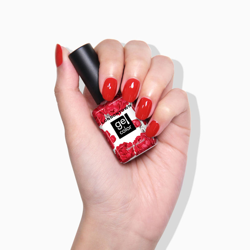 A hand with freshly painted Maraschino Cherry gel nails holds a LONDONTOWN red gel nail polish bottle featuring a floral label design.
