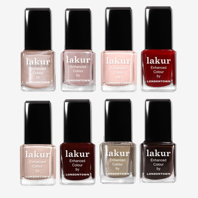 Eight LONDONTOWN Merry Minis Set Lakur nail polishes are arranged in two rows, displaying shades from nude and pink to red, burgundy, and metallic gold.