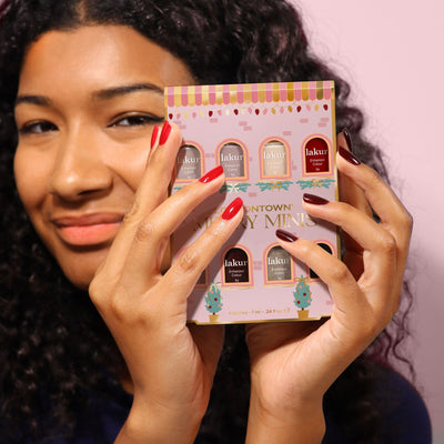 A person with curly hair holds up a LONDONTOWN Merry Minis Set, showing off multicolored polished nails.