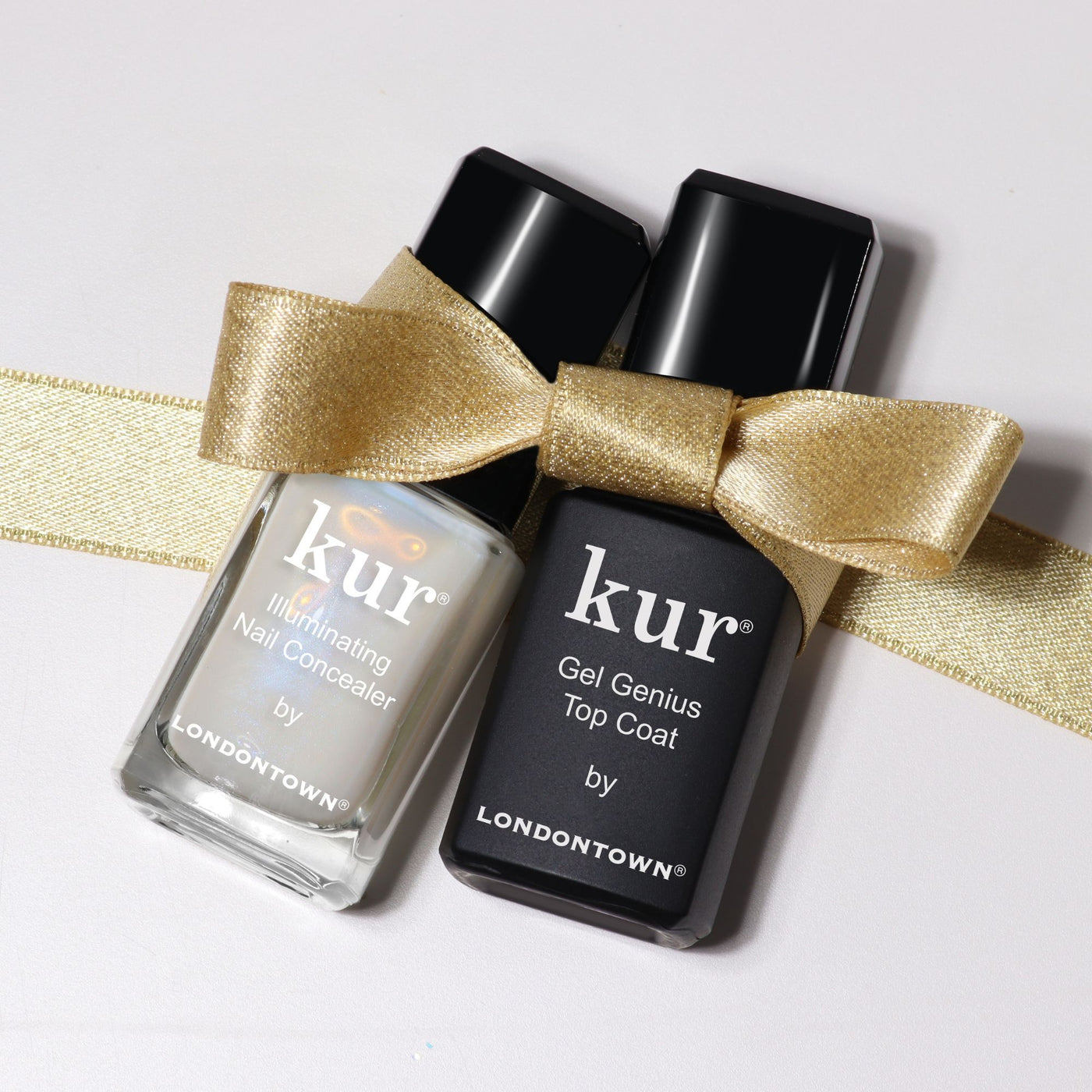 LONDONTOWN’s Conceal & Go: Holiday Edition features two nail essentials wrapped with a gold bow on a light background—everything you need for perfect nails this holiday season.