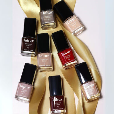 Eight bottles from the LONDONTOWN Merry Minis Set, arranged in various shades on a gold satin ribbon against a light background.