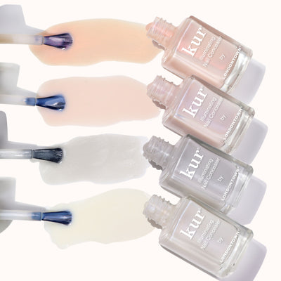 Four open bottles of LONDONTOWN The Concealer Wardrobe, each displaying a different polish shade swiped on a light background—perfect for easy, one-step flawless nail care.