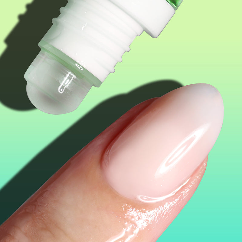 Close-up of a LONDONTOWN Roll & Glow Cuticle Oil - Agave Pear rollerball applicator dispensing the sweetest cuticle oil onto a fingertip against a green gradient background.