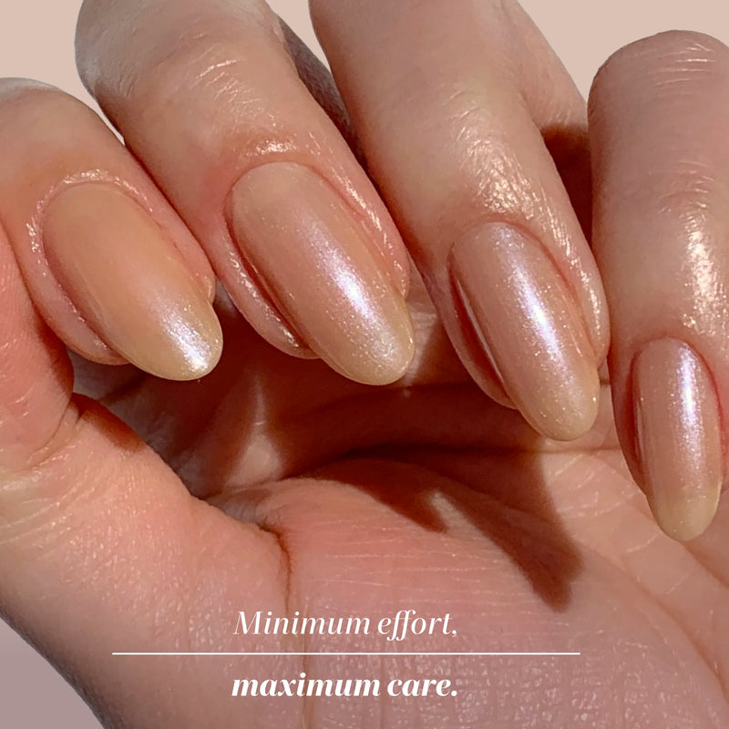A hand with neatly manicured, natural-colored, glossy nails using LONDONTOWN Bare Illuminating Nail Concealer. Text: "Minimum effort. Maximum care.