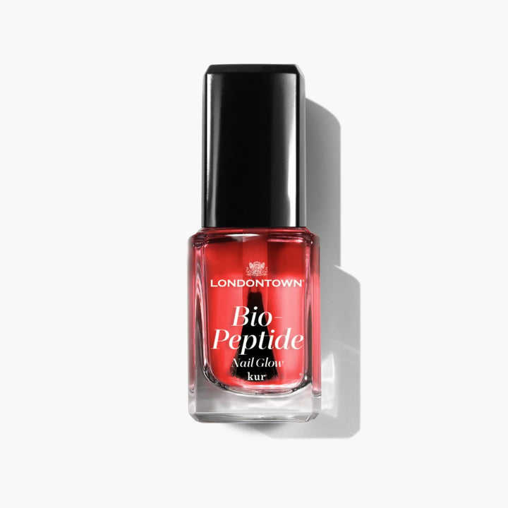 Bottle of LONDONTOWN Bio Peptide Nail Glow in sheer red with a black cap, perfect for a glowing skin aesthetic.