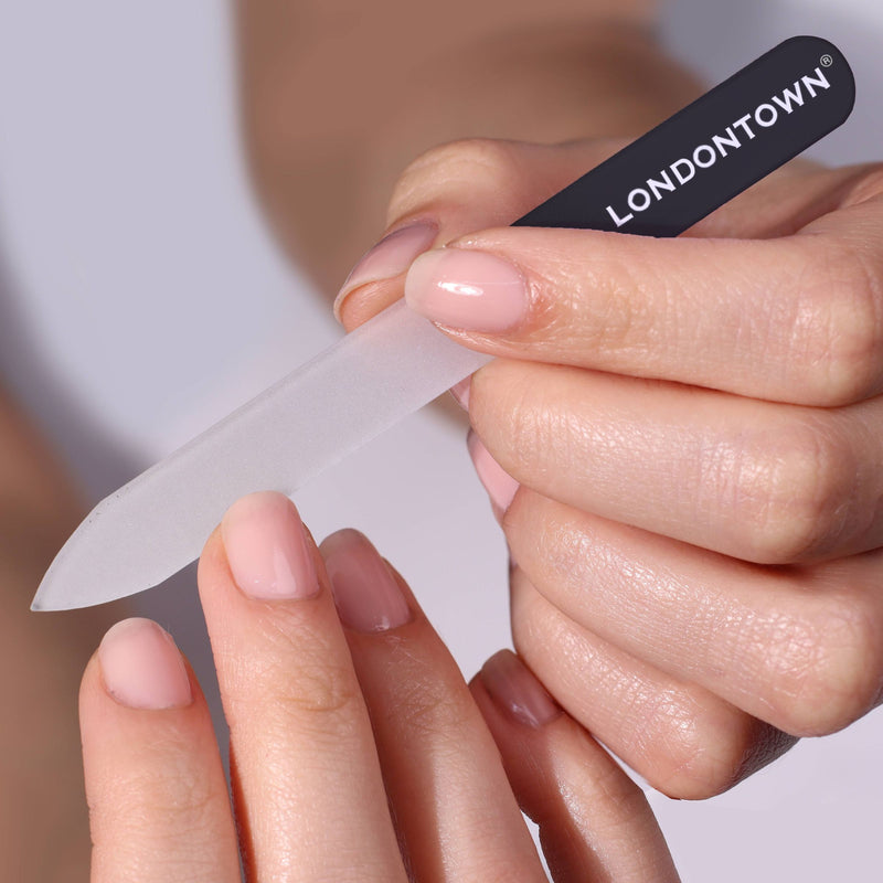 A person is effortlessly using a LONDONTOWN Glass Nail File - Black to shape their nails, ensuring a damage-free nail filing experience.