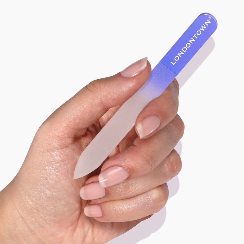 A hand holding a LONDONTOWN Glass Nail File - Lilac, making nail filing effortless and reducing damage.