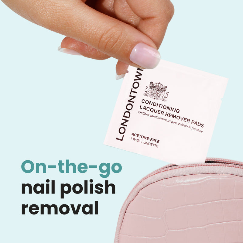 A hand holds a LONDONTOWN Conditioning Lacquer Remover Pad above a pink pouch, ideal for nail polish removal on the go.