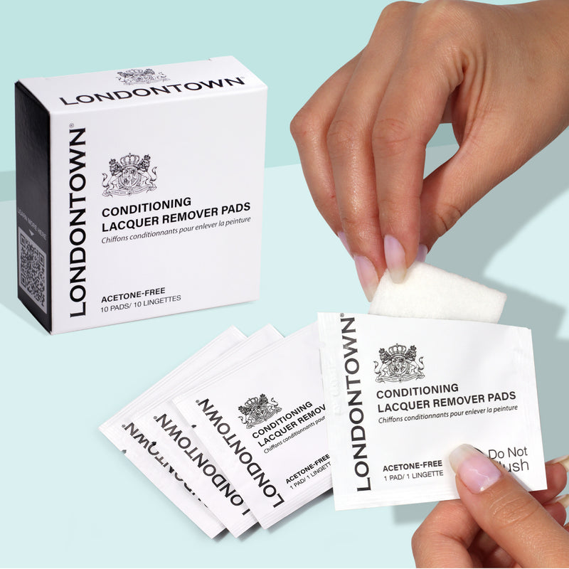 An individual opens a package of LONDONTOWN Conditioning Lacquer Remover Pads, ideal for convenient nail polish removal while traveling. Each sachet reveals a pad that is ready to use.