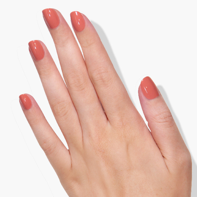 A human hand with neatly manicured nails painted in a glossy, Cactus Coral color from LONDONTOWN, shown against a lush white background.