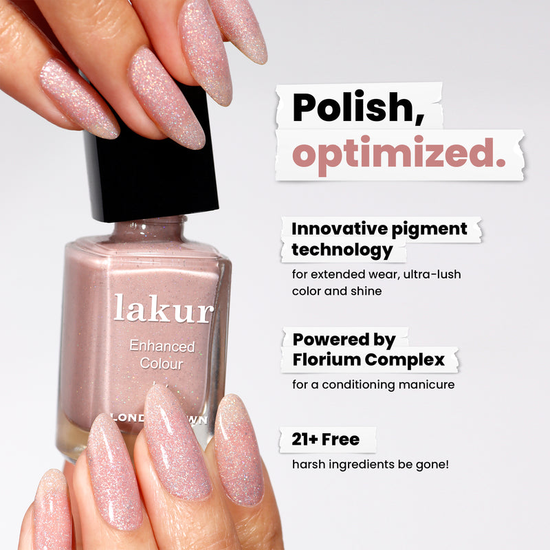 Hands hold a bottle of LONDONTOWN's "Champagne in Bed," a light pink glittery nail polish with neutral pink sparkle. Featuring pigment technology, Florium Complex, and a 21+ free formula for lasting wear and shine.