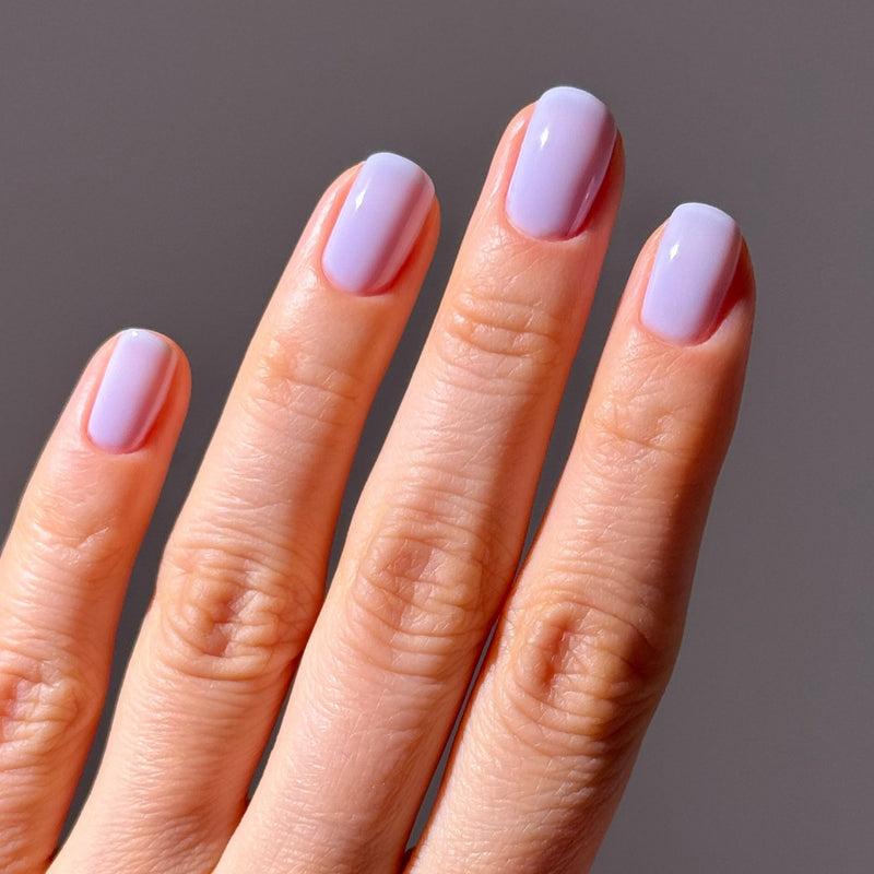 A hand with four fingers visible, featuring neatly manicured nails painted in LONDONTOWN's Cloud Nine—a dreamy periwinkle—shown against a plain background.