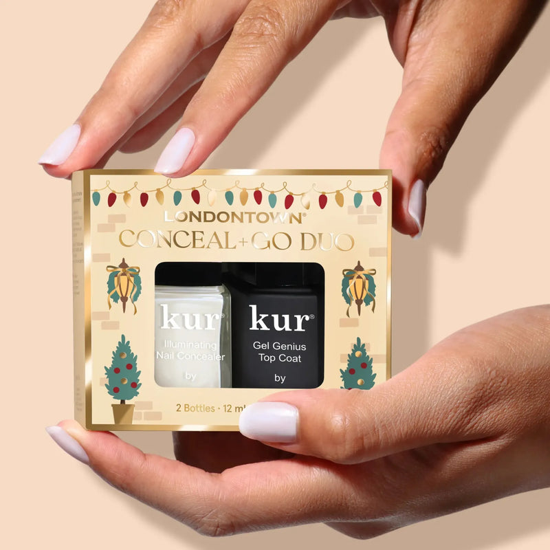 Someone holds a LONDONTOWN Conceal + Go: Holiday Edition nail care set with two bottles in festive packaging—perfect for naturally flawless nails.