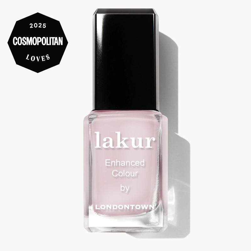 A bottle of LONDONTOWN Lakur Enhanced Colour nail polish in the shade Strawberry Milk, a sweet milky pink, with a “2025 Cosmopolitan Loves” badge in the top left corner.