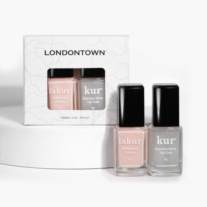 Two bottles of LONDONTOWN's Royal Manicure, one labeled "lakur Enhanced Colour" and the other "kur Diamond Shine Top Coat," exude sophistication as they sit shimmering in front of their packaging.