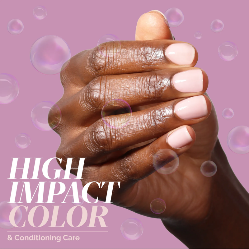 A hand with neatly manicured, light pink nails—painted in LONDONTOWN’s Dream State—is shown against a pink background with translucent bubbles, glowing softly, alongside the text “High Impact Color & Conditioning Care.”.
