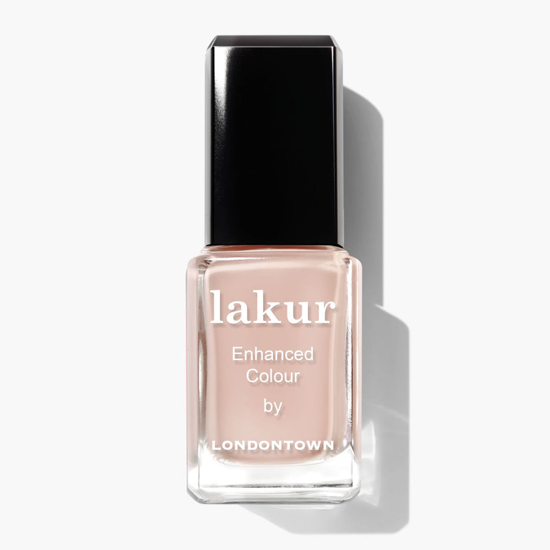 A bottle of LONDONTOWN's Lakur Enhanced Colour nail polish in the shade Dusk, a pale nude hue with a hint of peach and topped with a black cap, photographed against a white background.