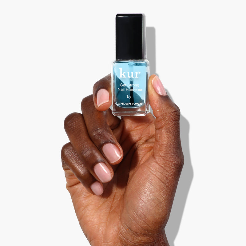 A hand holding a bottle of Get Strong Nail Hardener by LONDONTOWN, an essential for those dedicated to nail care and achieving the strongest nails.