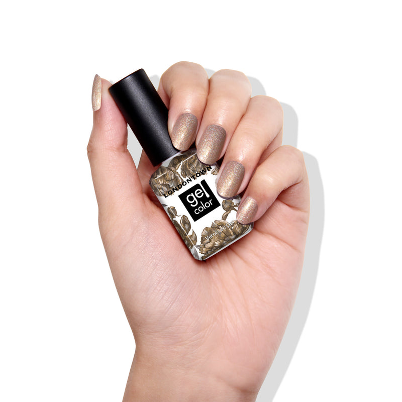 A hand displays neatly manicured nails painted with LONDONTOWN's You're Golden gel nail polish, featuring holographic gold and metallic brown shades.