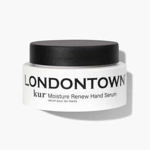 A jar labeled "Moisture Renew Hand Serum" from LONDONTOWN, featuring a white container and black lid, promises to be the restorative rescue for even the driest hands.