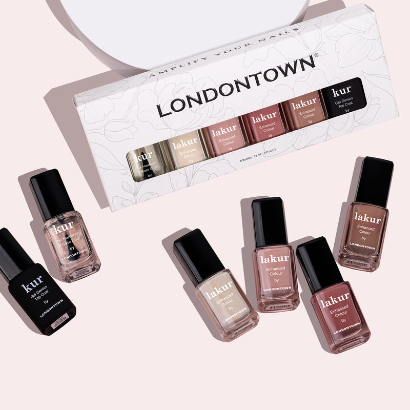 A collection of LONDONTOWN nail polishes, known as The Sophisticate Collection, featuring four neutral Lakur shades and a Kur top coat, is arranged on a light surface. The set is beautifully displayed in a branded white box.